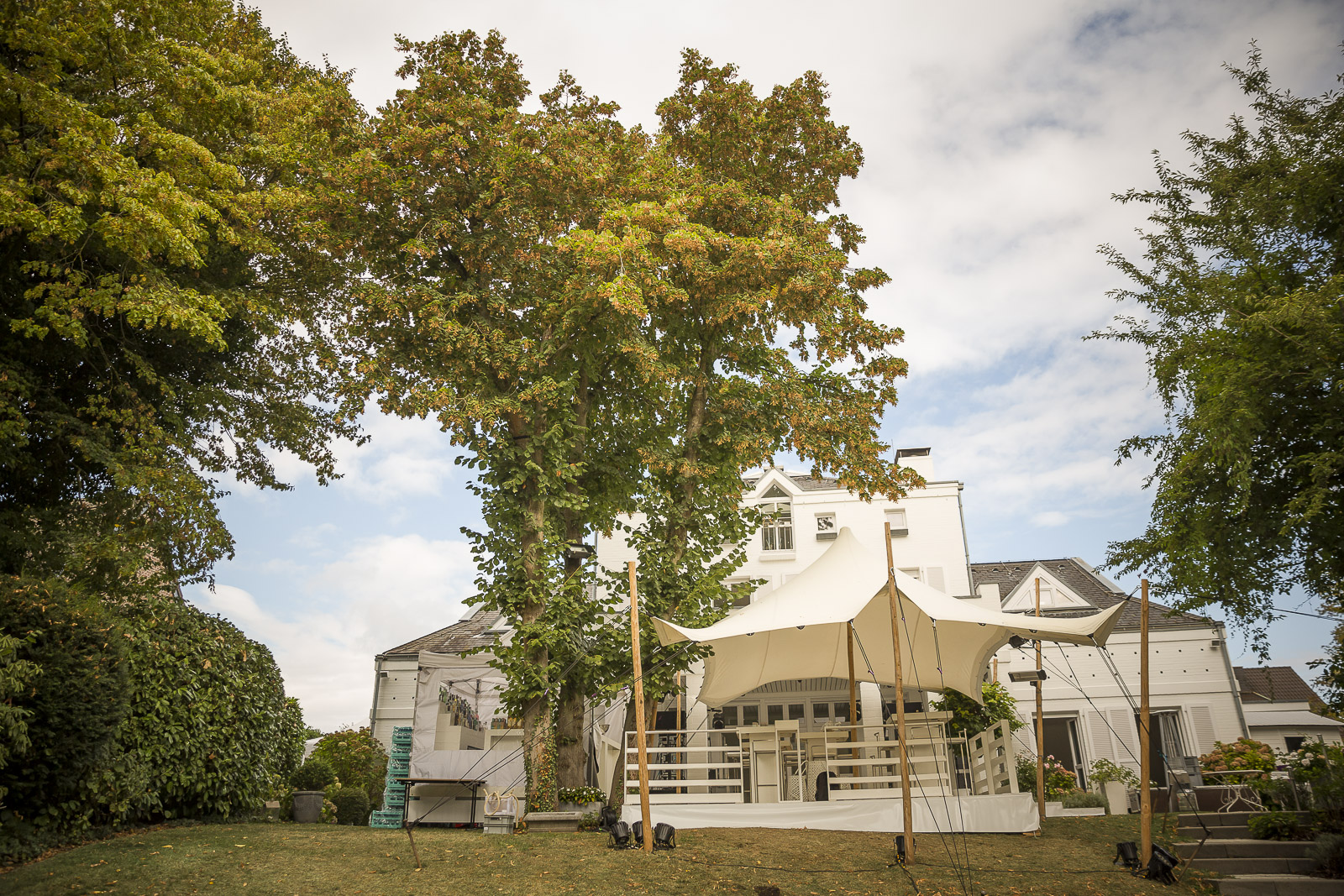 Tente stretch beige installée pour une réception privée devant une maison de caractère