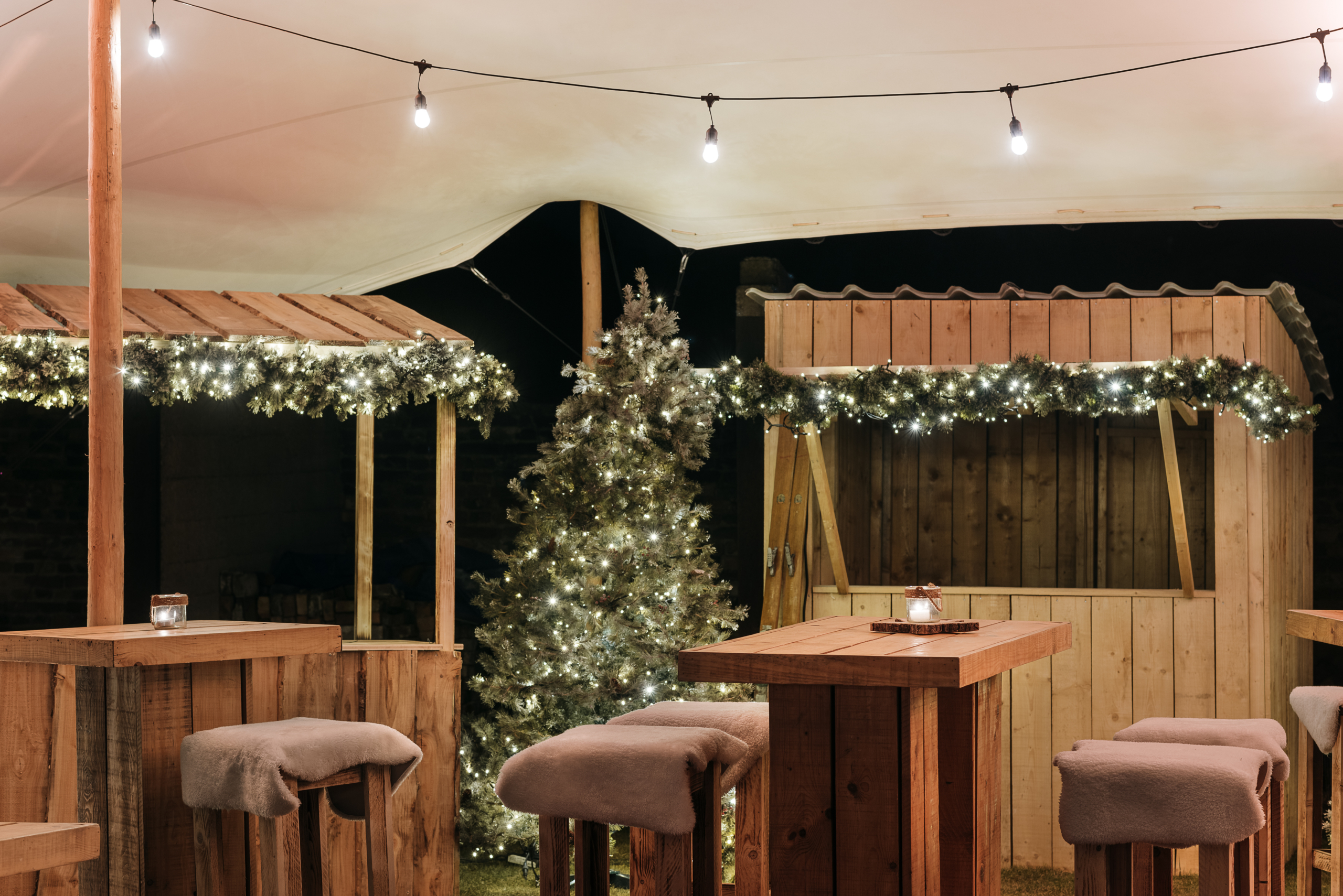 Chalet de Noël en bois sur une place avec des espaces pour accueillir les visiteurs