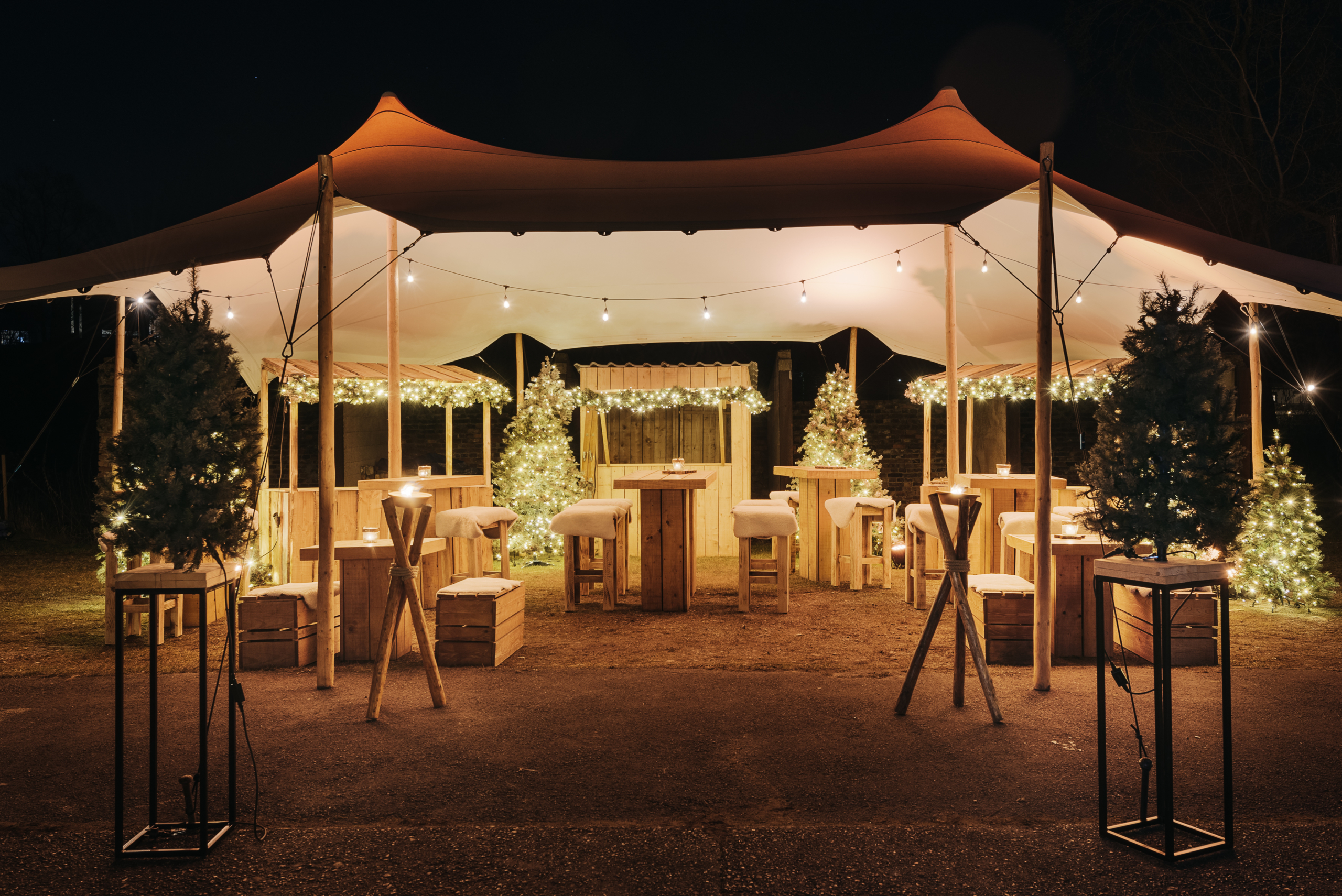 Tente stretch avec chalets de Noël en bois installés sous la toile